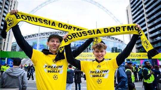 Zwei Fans von Borussia Dortmund stehen mit einem BVB-Fan-Schal vor dem Wembley-Stadion.
