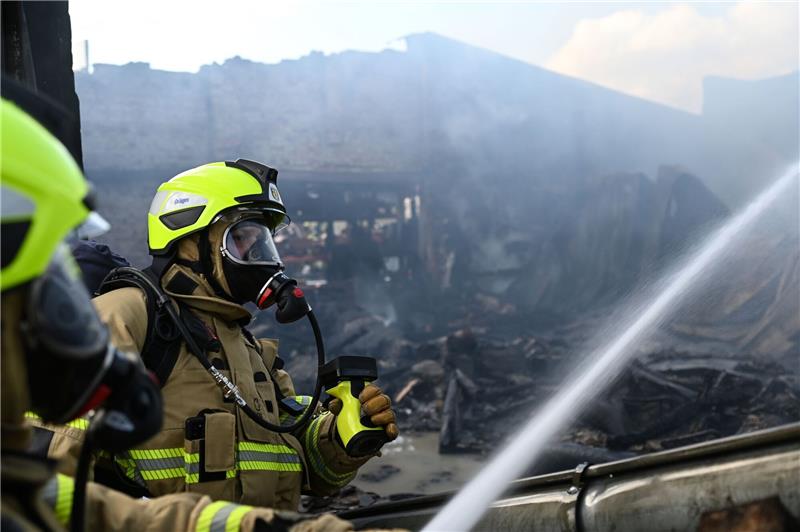 Zwei Feuerwehrmänner löschen das Feuer in der Halle.