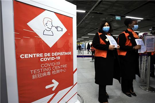 Zwei Flughafenmitarbeiterinnen warten auf dem französischen Flughafen Roissy-Charles de Gaulle auf Passagiere aus China.