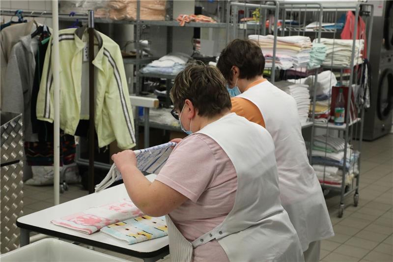 Studie sieht Benachteiligung von Menschen mit Handicap Zwei Frauen arbeiten in der Wäscherei der Lebenshilfe Gera e.V und legen dort Wäsche zusammen.
