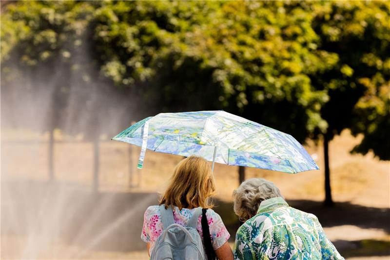 Sommer-Zeit ist Sonnenschutz-Zeit Zwei Frauen schützen mit einem Regenschirm vor der Sonne.