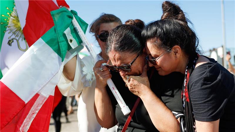 Zwei Frauen umarmen sich während einer Demonstration.