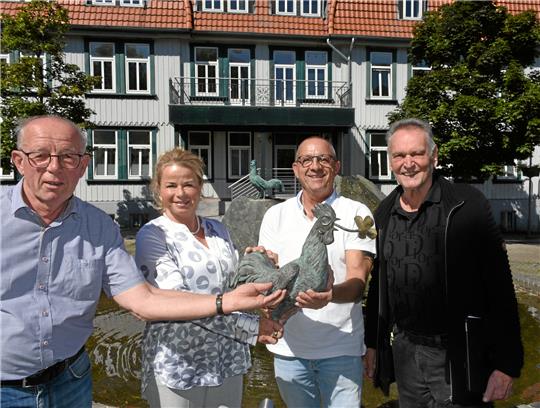 Zwei Hähne für Hahnenklee (v.li.): Heinrich Wilgenbus, Urte Schwerdtner, Christian Hellmeier und Klaus Elders präsentieren auf dem Paul-Lincke-Platz zwei Wahrzeichen: Auf dem Brunnen thront ein neuer Hahn, der alte wurde 2018 gestohlen und kam jetzt per Paketpost zurück. Foto: Kempfer