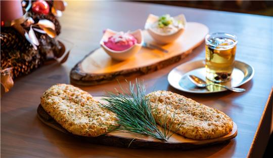 Zwei Kiefernnadeln-Foccacia liegen auf einem Tisch in der Waldkräuterey.