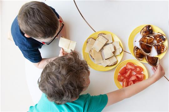 Zwei Kinder sitzen zum Frühstück in einem Kindergarten am Tisch. Das Land hat 200 Millionen Euro an die Kommunen weitergereicht, um einen Anstieg der Kosten für Energie und Essen zu dämpfen. Foto: dpa