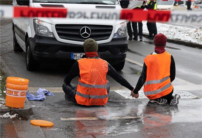 Nach Razzia: „Letzte Generation” protestiert weiter Zwei Klimaaktivisten der «Letzten Generation» versuchen, sich auf einer Straße in München trotz Nieselregen und Minusgraden festzukleben.