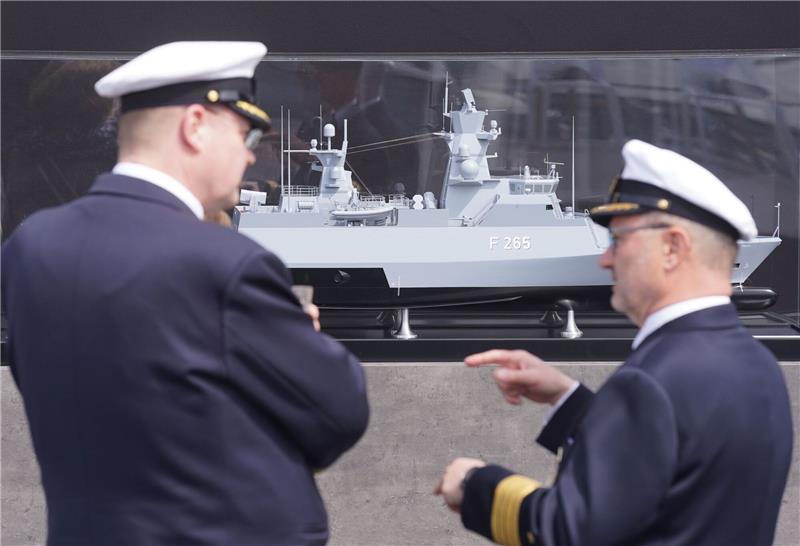 Zwei Marinemitglieder stehen vor einem Modell vor der Taufzeromonie der Korvette F 266 "Emden" auf dem Werftgelände von Blohm+Voss im Hafen.