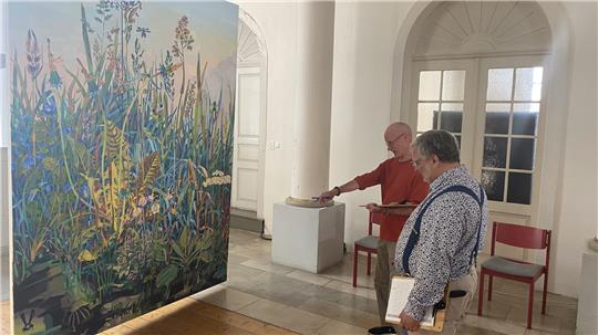 Zwei Mitglieder der Jury betrachten in der Martini-Kirche das Siegerbild des Jahres 2024.