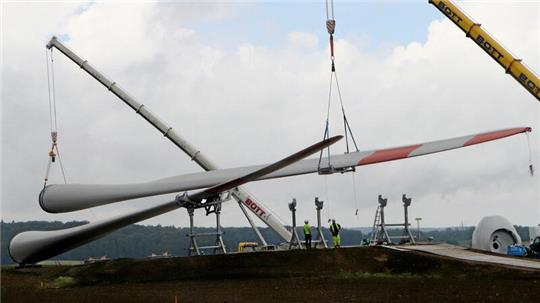 Zwei Mobilkräne heben das Rotoblatt vom Lkw an die richtige Ablegestelle. Der Schwertransport hat Überlänge und misst 90 Meter.