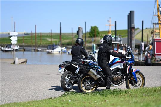 Zwei Motorradfahrer starten zu einer sommerlichen Tour im Hafen von Ditzum.