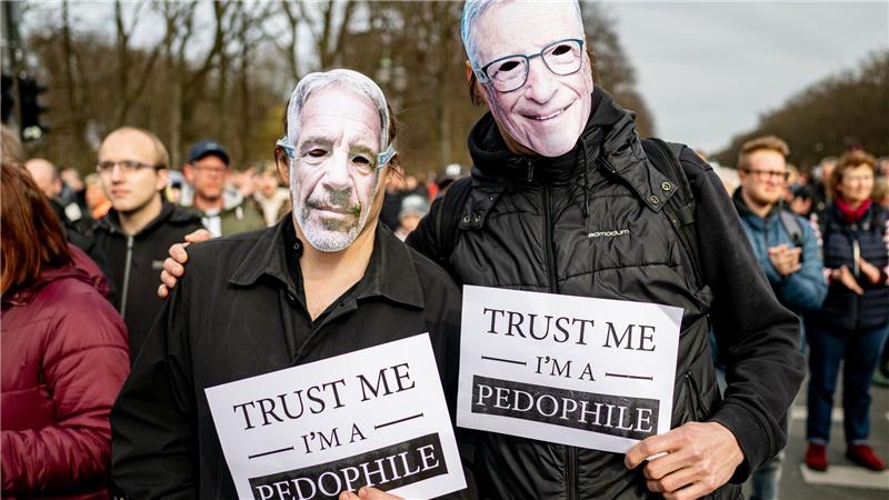 Zwei Personen nehmen an der Demonstration „Transparenz, Rechtsstaat und Schutz von Minderjährigen“ mit einer Maske von Jeffrey Epstein (l) und Bill Gates mit einem Schild mit der Aufschrift „Trust me I‘m a pedophile“ teil. 