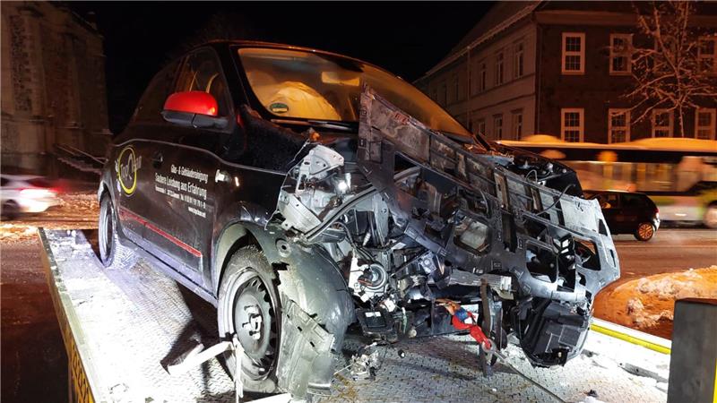 Ein dunkler Kleinwagen, der vorne komplett zerquetscht ist.