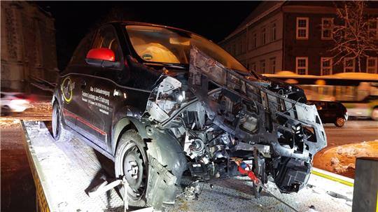 Ein dunkler Kleinwagen, der vorne komplett zerquetscht ist.