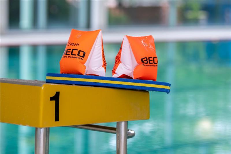 Mehr junge Nichtschwimmer: Wie sollen Kinder schwimmen lernen? Zwei Schwimmflügel und ein Schwimmbrett liegen auf einem Startblock.