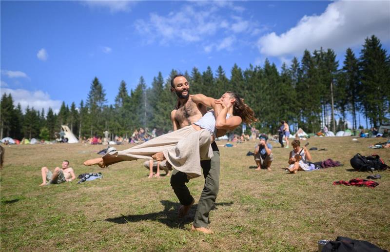 Zwei Teilnehmer tanzen ausgelassen bei einem Zeltlager. 