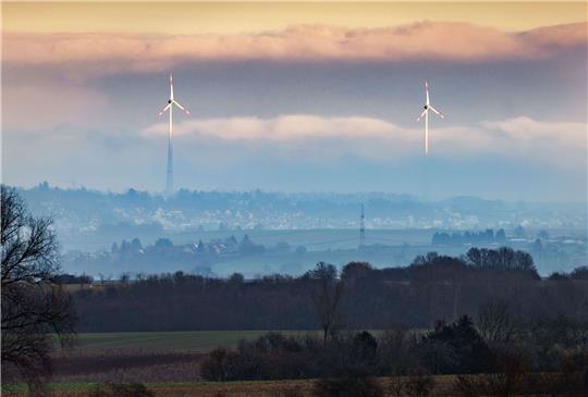 Zwei Windräder ragen aus dem Dunst über der Wetterau heraus.