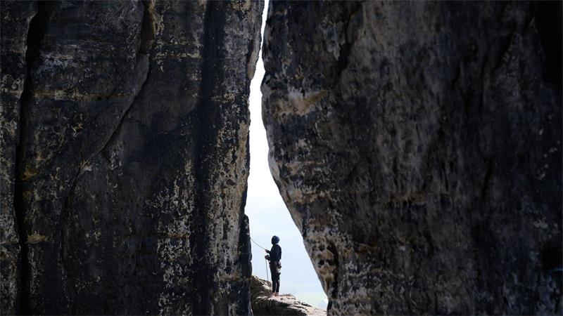 Zwischen zwei Felsen: Ein Kletterer sichert eine Kletterin am Felsen an der Basteibrücke in der Sächsischen Schweiz ab.
