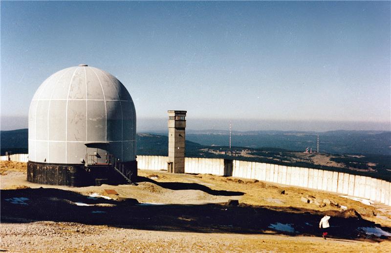 <p>Blick vom Brockenplateau, das noch von einer Mauer umschlossen ist, zum Torfhaus Anfang der 1990er Jahre: Links ist die Abhöranlage der DDR-Staatssicherheit zu sehen. Die Antennenkuppel wird auch als Radom bezeichnet.  Foto: Brockenhaus</p>