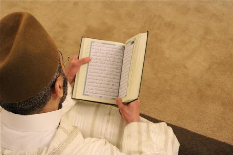 <p>Ein Gläubiger liest im Koran. Symbolfoto: Unsplash/Rachid Oucharia</p>