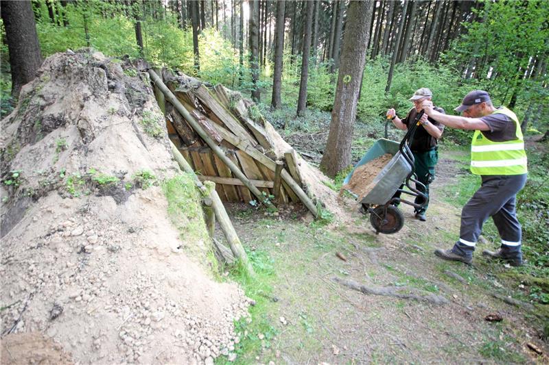 <p>Henning Brunke und Wegewart Bernd Sprengel (v. li.) karren neuen Boden heran, um den Meiler abzudecken. Foto: Gereke</p>